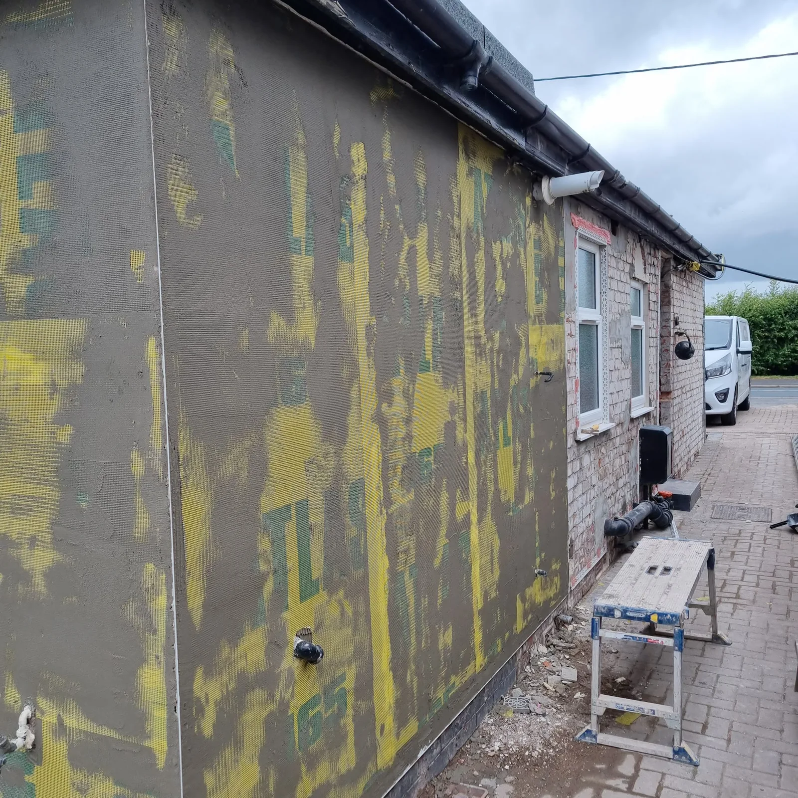 Atlas basecoat on a side elevation beside untouched original brickwork, Southport