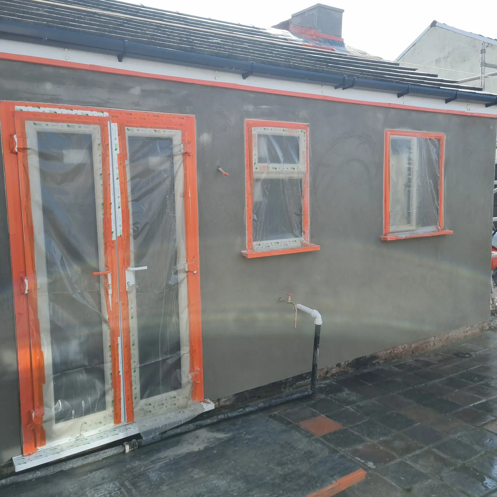 Grey basecoat across a full rear elevation with openings masked, Southport