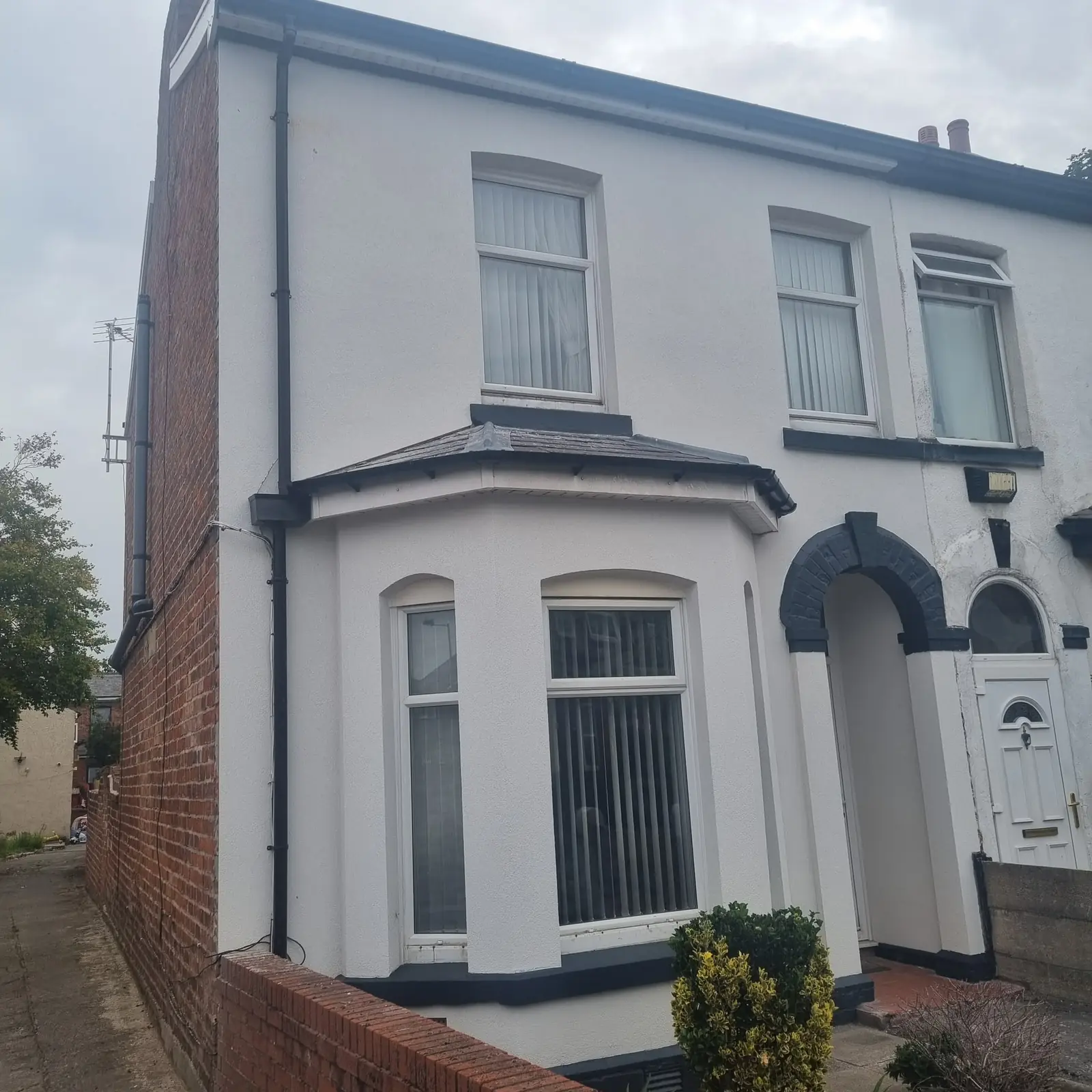 Bay and canopy of a Southport end terrace in white render with the dark grey band details picked out