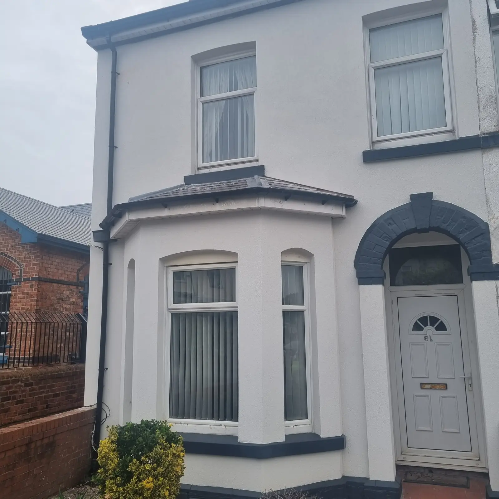 White render carried round the flank of a Southport end terrace beside the original brick wall