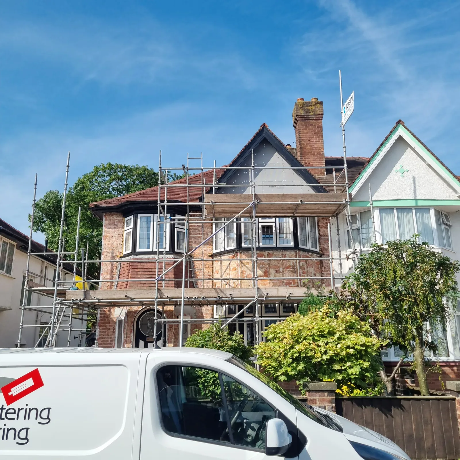 Failed old render stripped back to brick with scaffold up on a Southport house