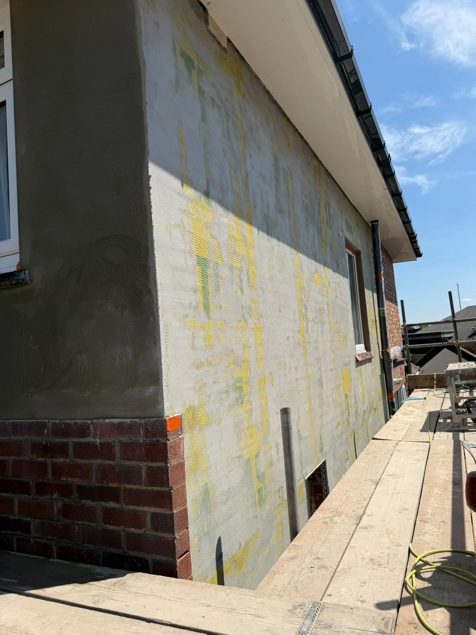 Alkali-resistant mesh bedded into basecoat over insulation board, Southport