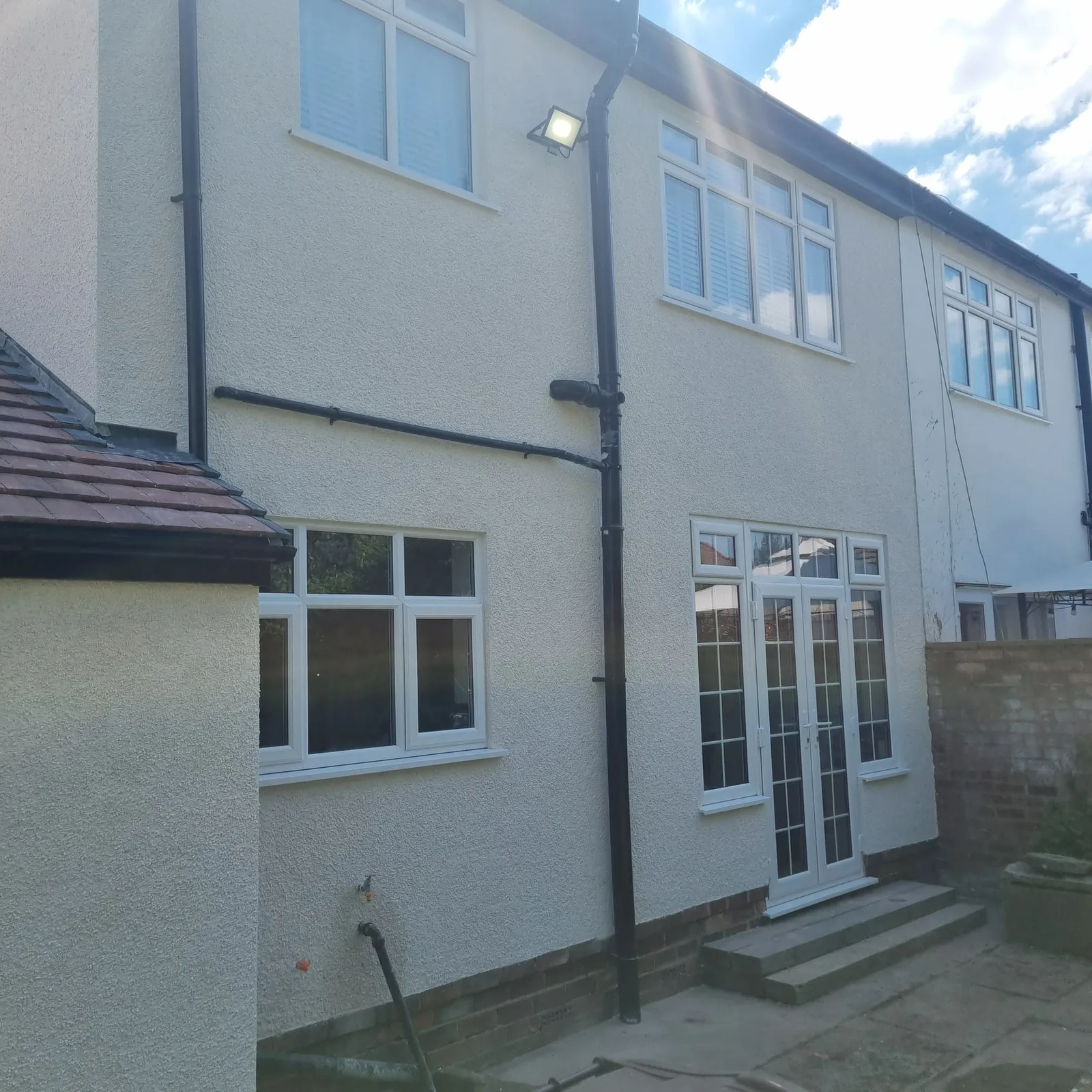 Two-storey rear elevation finished in cream render with French doors, Southport