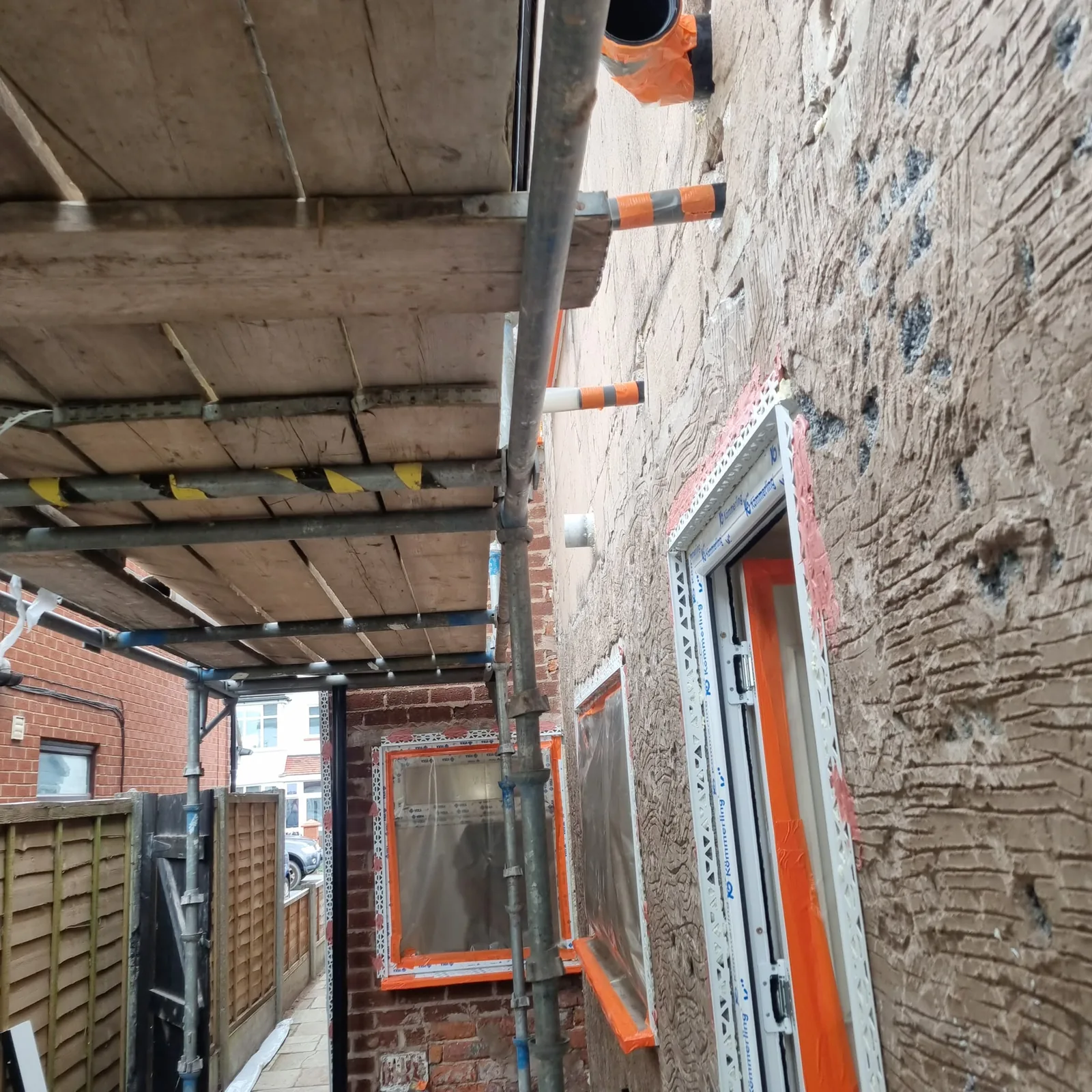 Failed sand-and-cement render hacked off to bare substrate in Southport