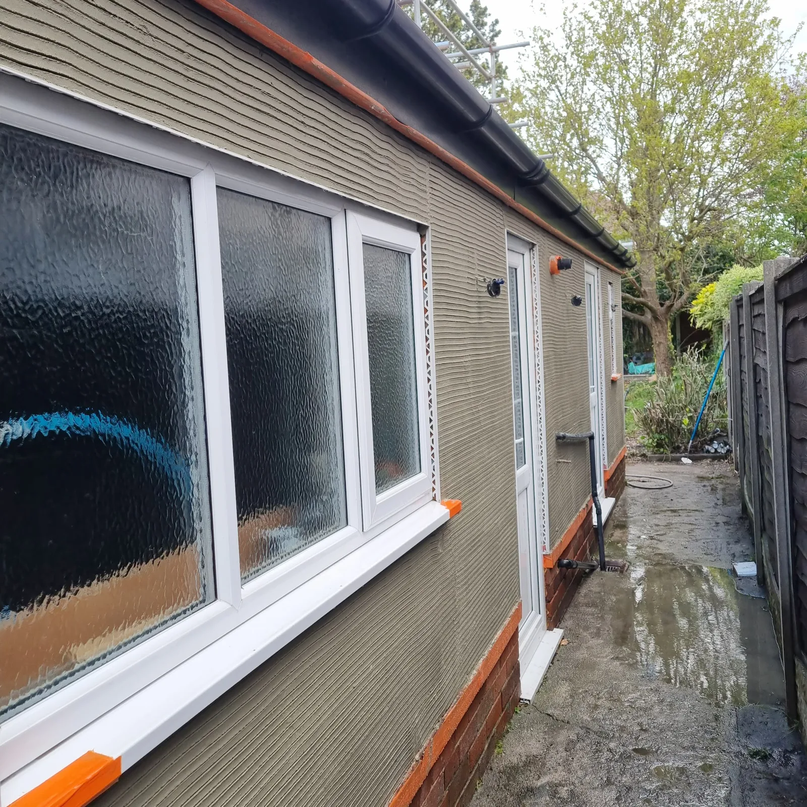 Combed basecoat with corner and stop beads set out on a Southport render job