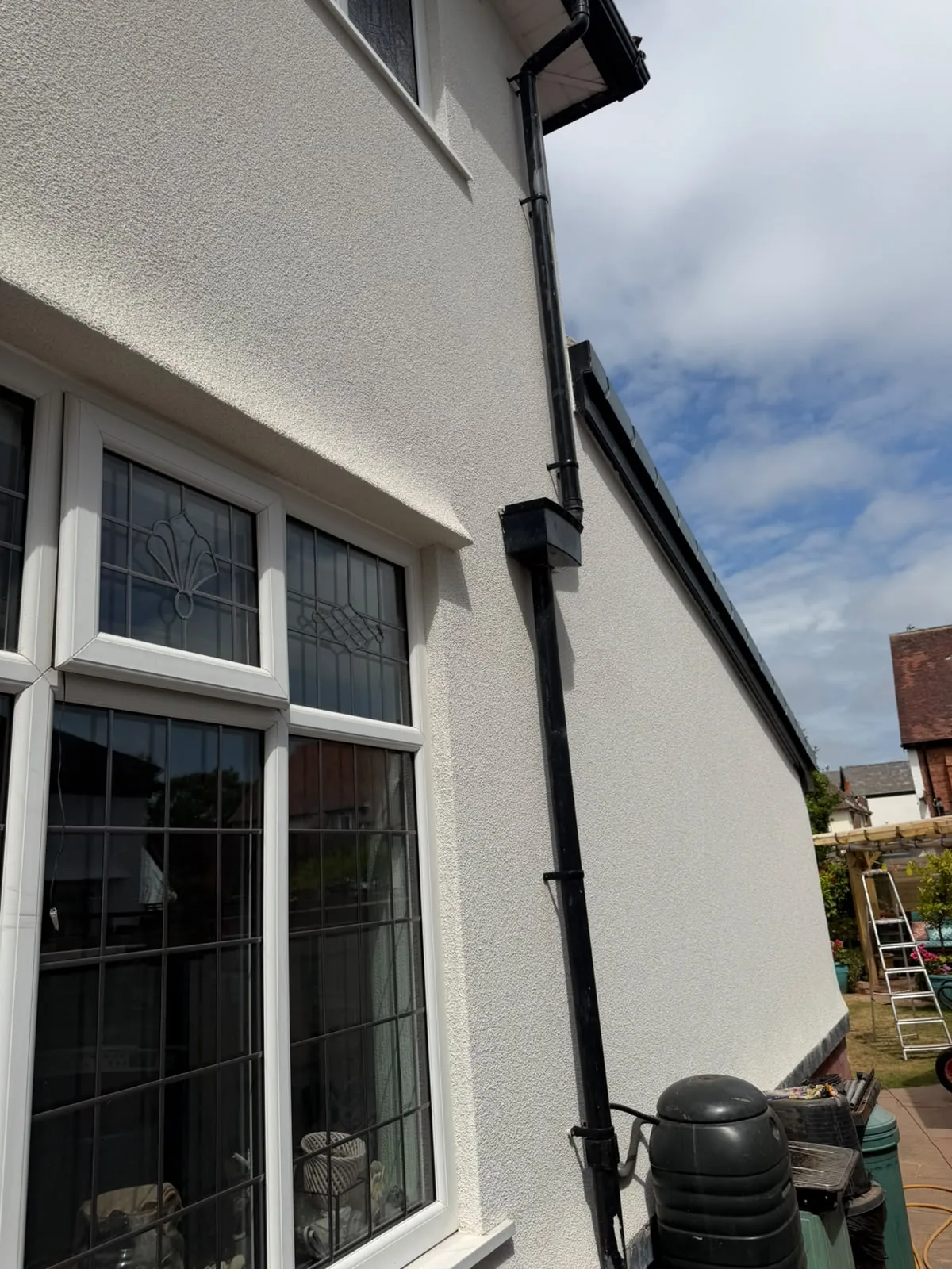 Finished silicone render on a bay window and downpipe detail in Southport