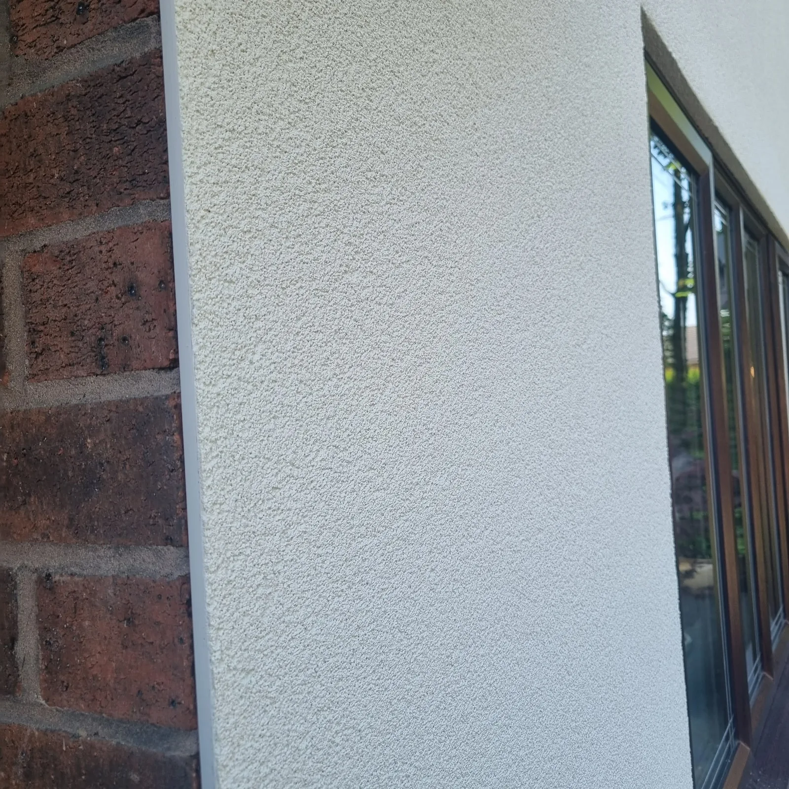 Finished silicone render texture meeting original brickwork on a Southport home